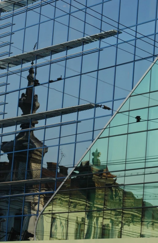 a clock tower reflected in a glass fronted building's windows