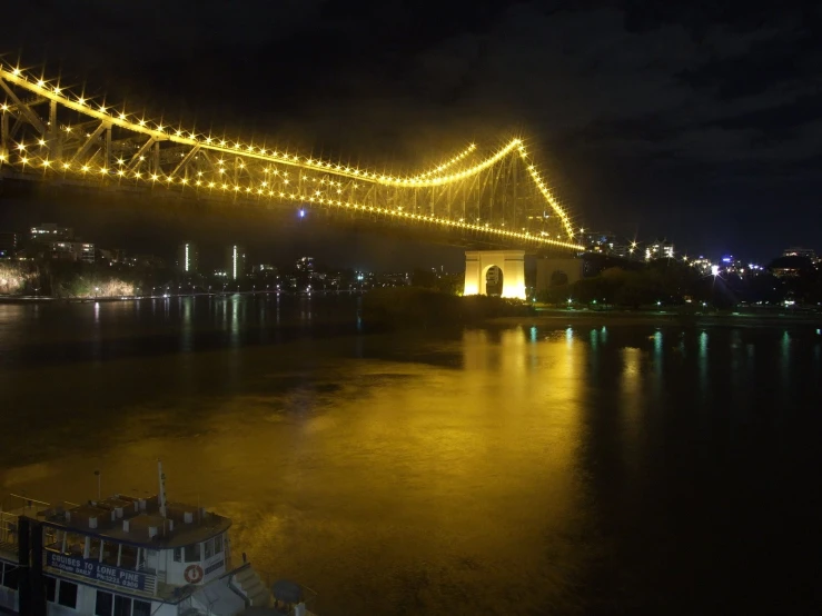 lights shine on a bridge over water at night