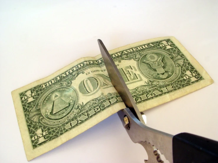 a dollar bill in front of a pair of scissors
