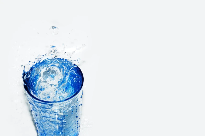 a plastic cup filled with water next to a white wall