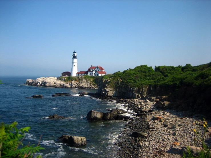 an ocean scene with rocks on both sides and a lighthouse on top