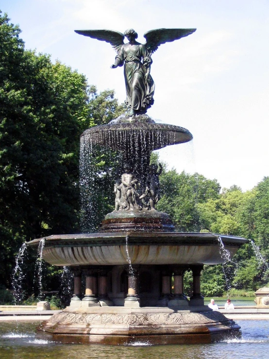 a fountain with an angel statue near a park