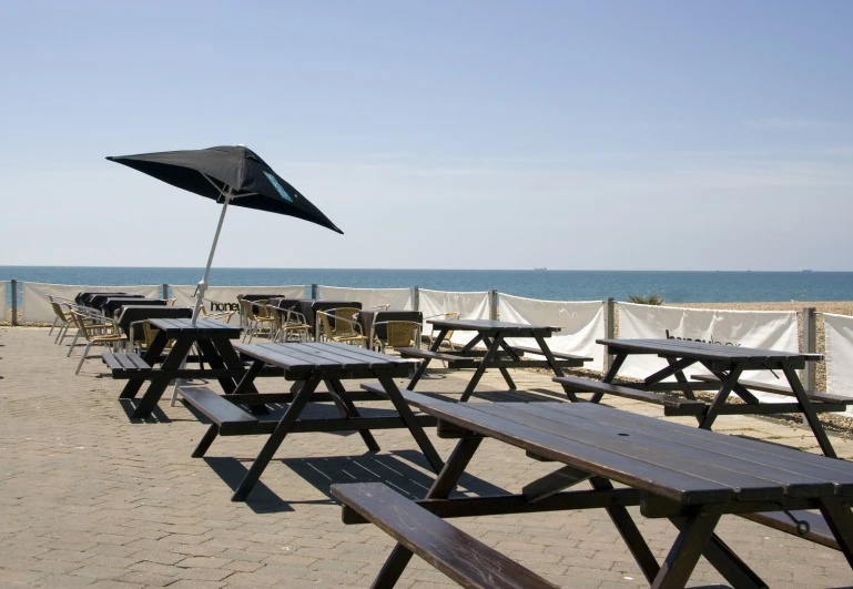 an outdoor area with tables and chairs next to the ocean