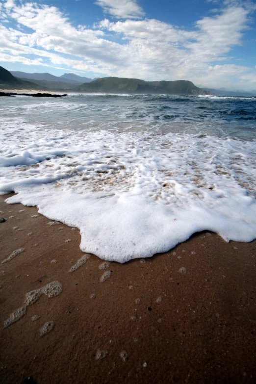 a sandy beach is shown under a partly cloudy sky