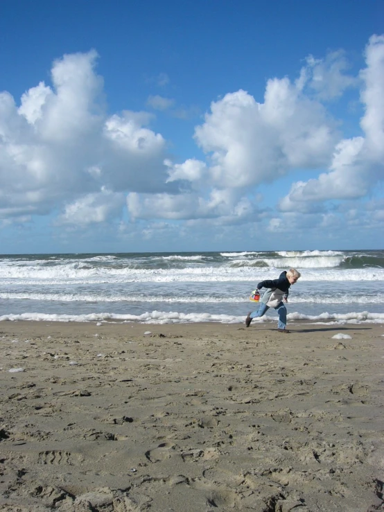 a boy is standing on a beach near the water