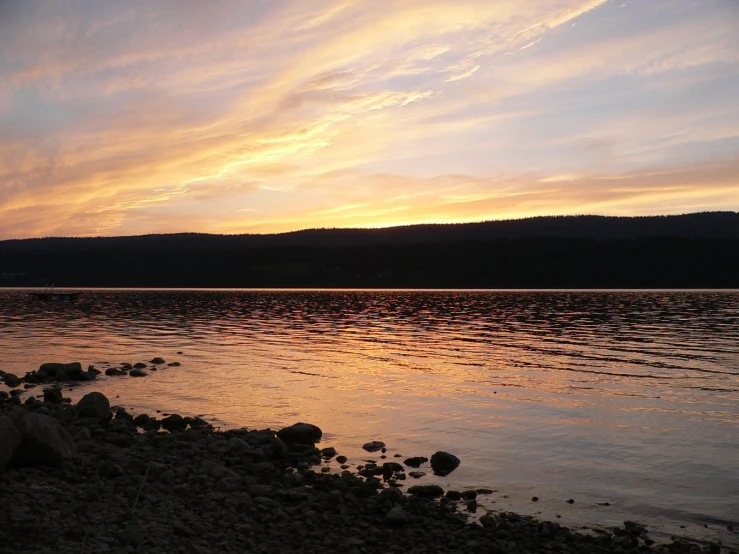 the sky is partly cloudy over a calm lake