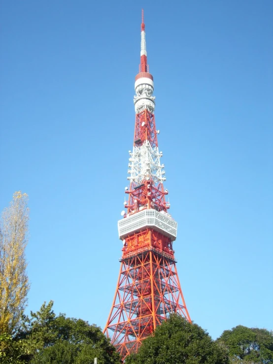 the tall red and white structure is next to some trees