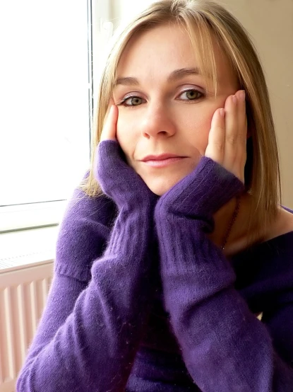 a woman poses for a po wearing a purple sweater