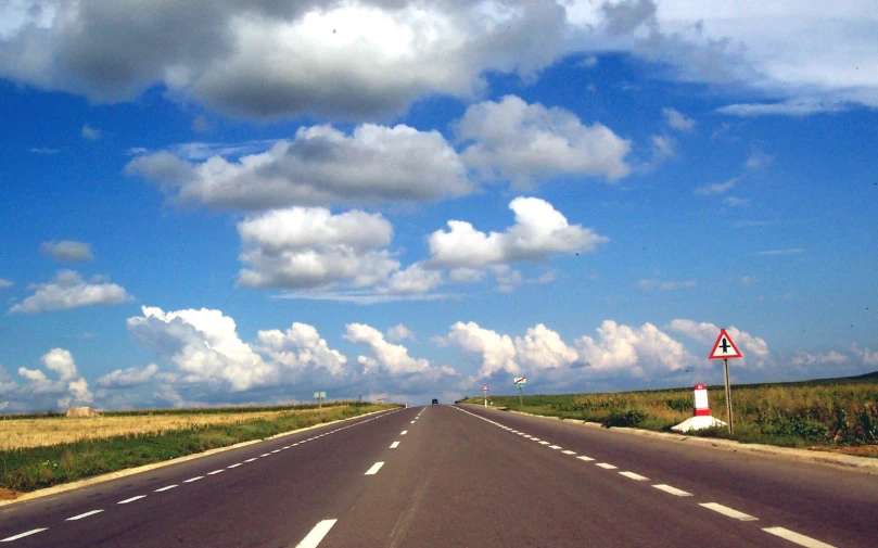 long asphalt road with a cloudy sky in the background