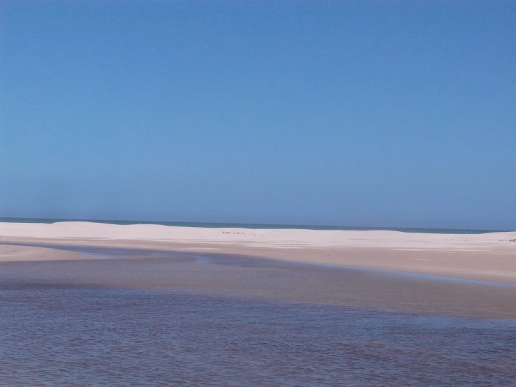 there is a man standing on the sand at the beach