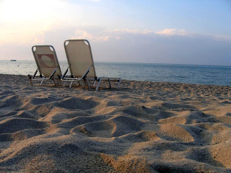 two lawn chairs on the beach, one without covers