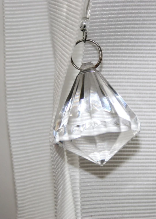 the clear pendant is hanging on a white piece