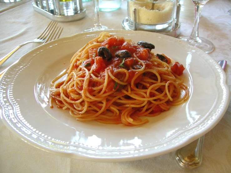 a white plate filled with spaghetti and olives