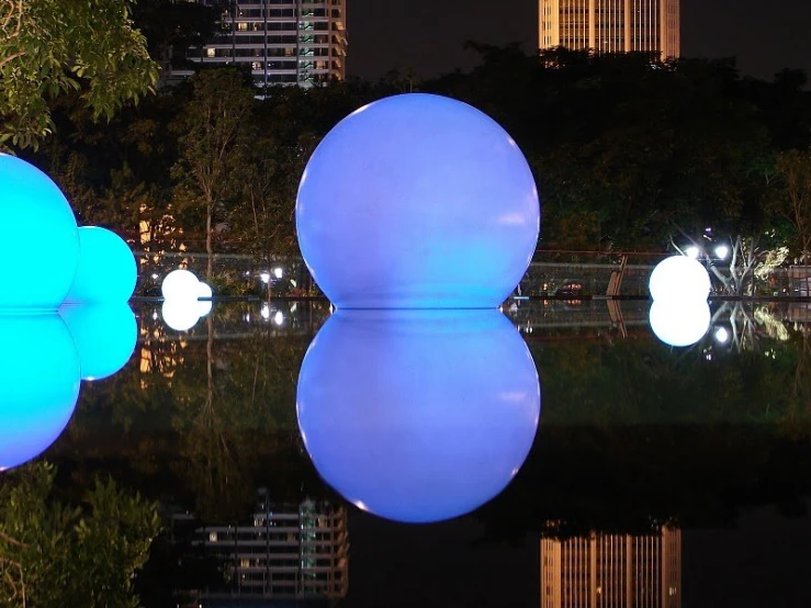 there are three giant balls by the water at night