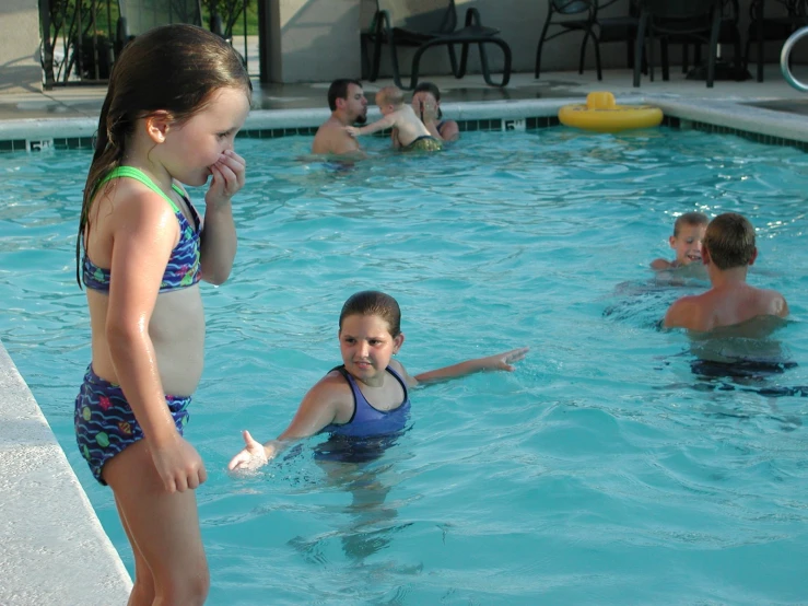 a small group of young children are playing in a pool