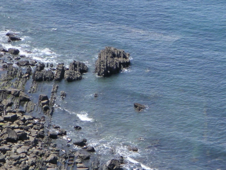 a group of rocks on top of the ocean near the shore