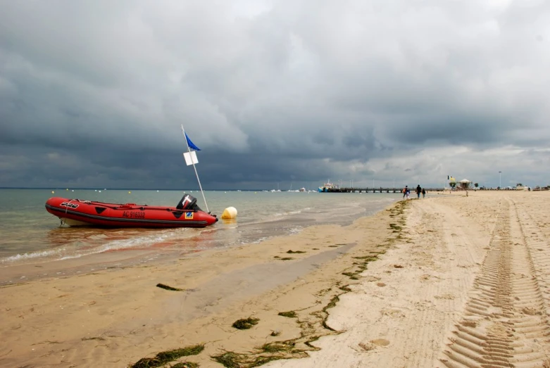 a red boat sitting on the beach next to people