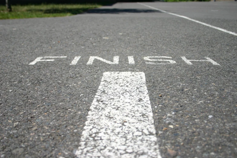 a cross walk is painted white and has a finish sign on it