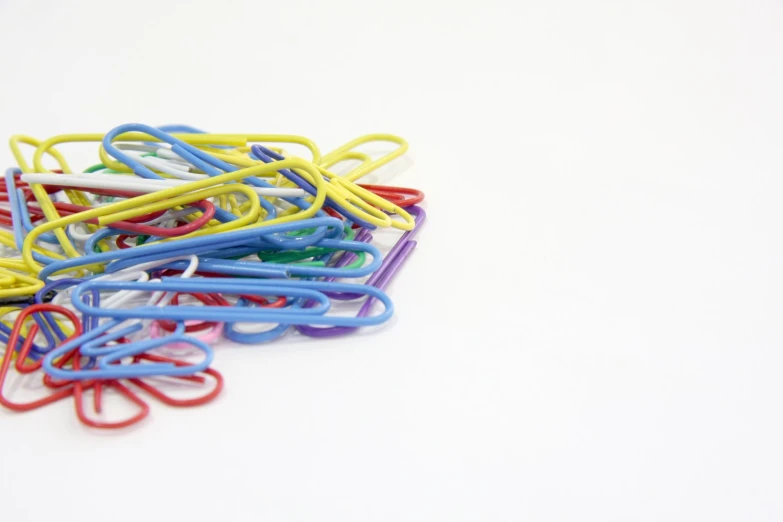 colorful paper clips on a white surface with a single toothbrush in each of them
