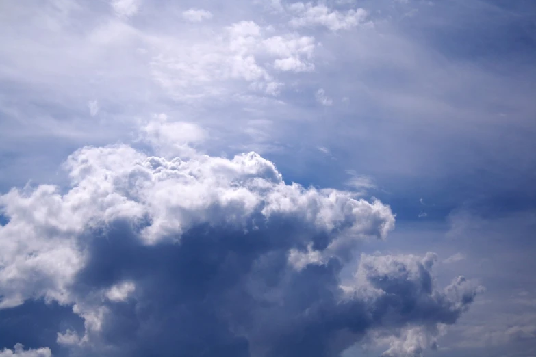 a jet flies under a cloud filled blue sky