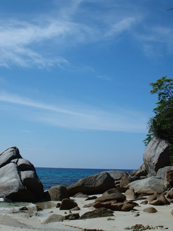 the blue sky is over the large rock near the ocean