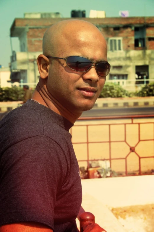 man with sun glasses sitting on tiled roof