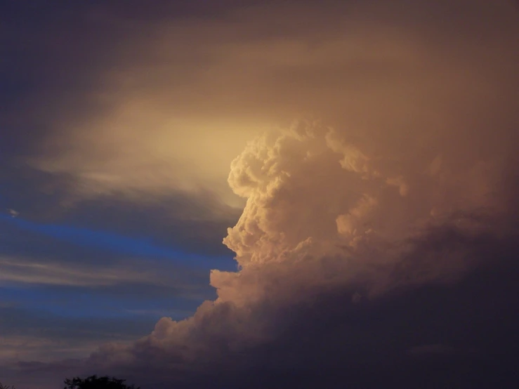 a very tall cloud in the distance under some clouds