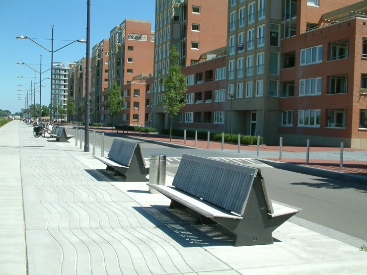 empty wooden benches sit on the sidewalk between two buildings