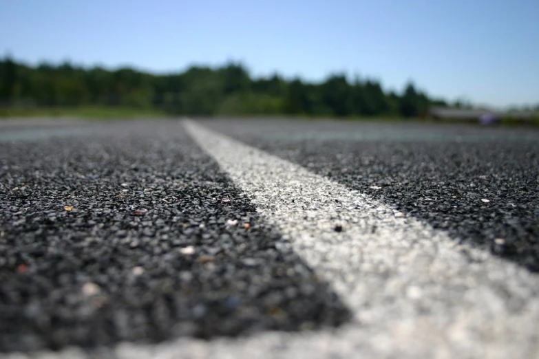 a long road lined with some asphalt in front of some trees