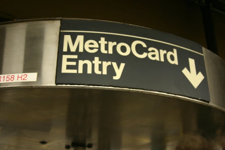 a metal circular sign with a arrow pointing towards the metro card entry
