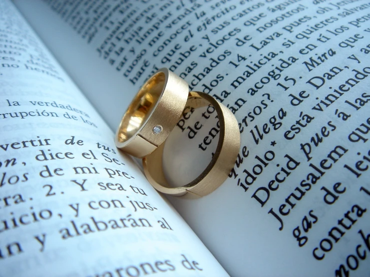 an open book with a wedding ring on top of it