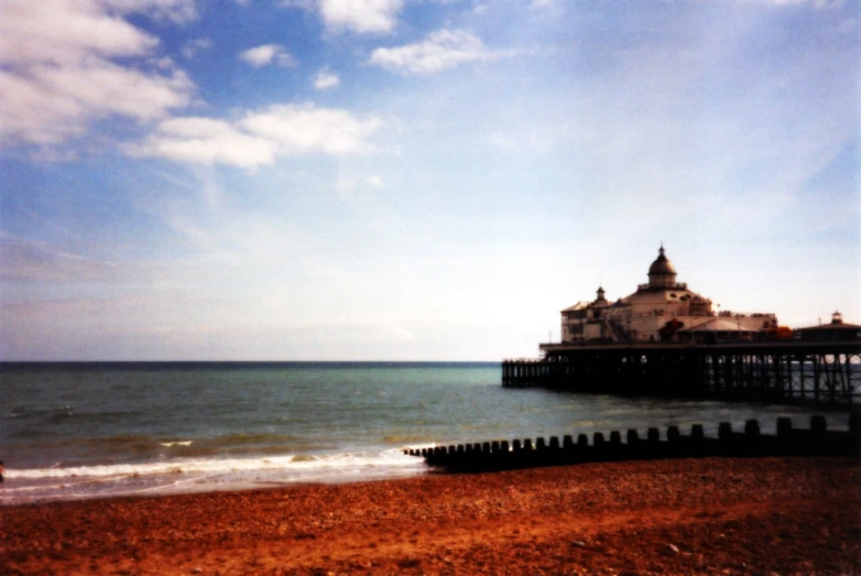 a small building near the ocean with clouds