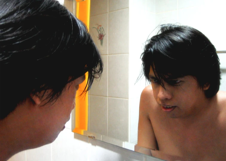 young male looking at himself in the mirror