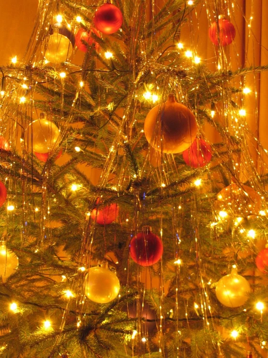 a christmas tree with lighted ornaments is decorated in bright yellow and red