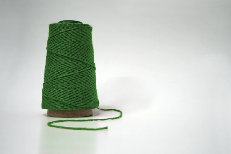 a spool of green colored thread with a piece of brown spool