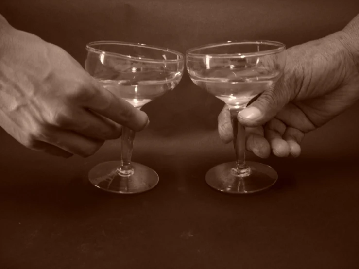 two hands with small glasses hold the wineglasses