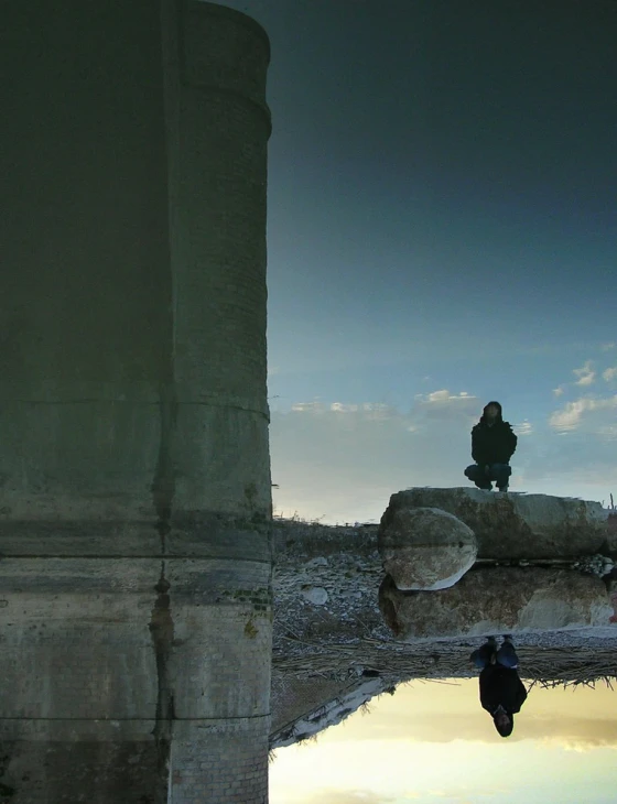 a person standing by a pond with a black umbrella