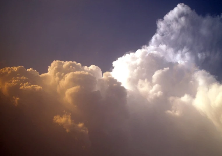 the airplane is flying in the sky with a lot of clouds