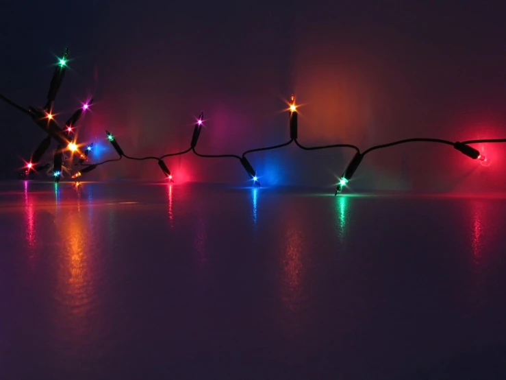 a string of lights sitting on the side of a body of water
