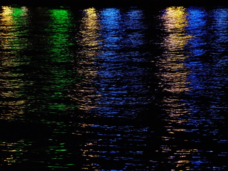 the city lights are reflected on the water