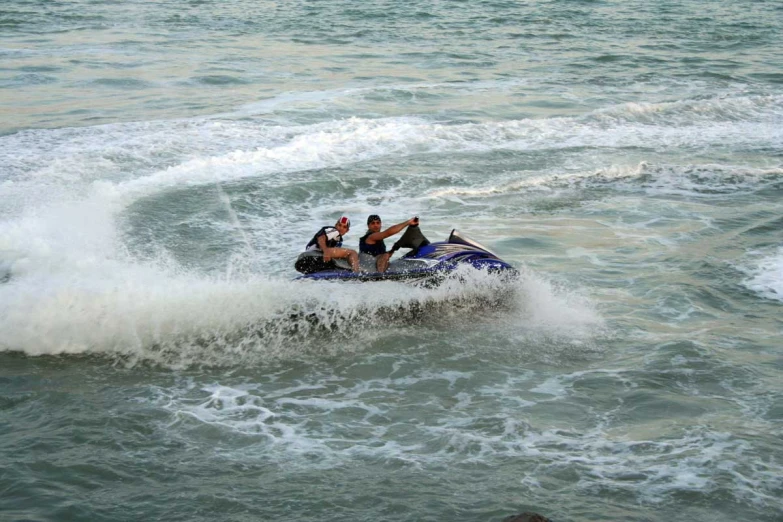 three people riding the back of a blue and white jet ski