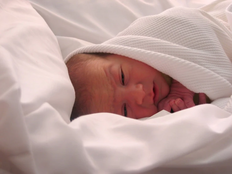 an infant baby is wrapped in white blanket