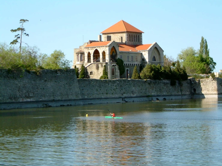 people paddling a kayak through a river with a castle like building in the background