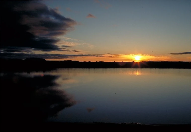 the sunset reflecting on the water of a large body of water