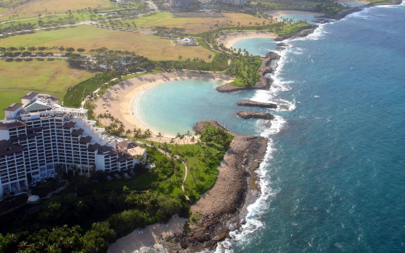 a big body of water next to a shore and lush green hills