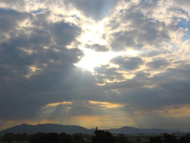 the sun shining through clouds above a field