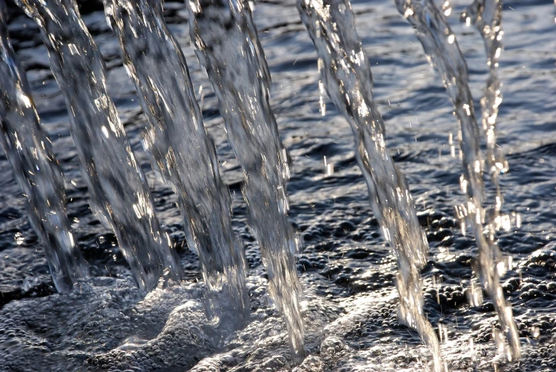 several spigots that are flowing out from a pipe in the water