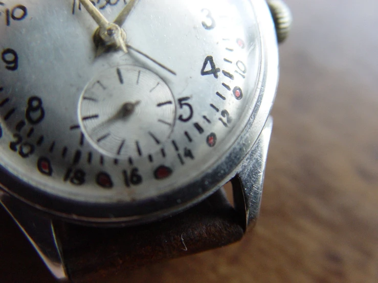 a close up of a watch on a wooden surface