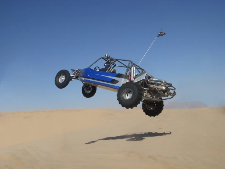 a blue truck flying over the sand