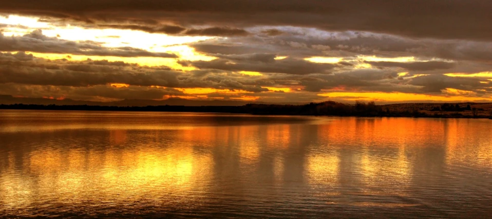 sunset reflected in the water with dark clouds